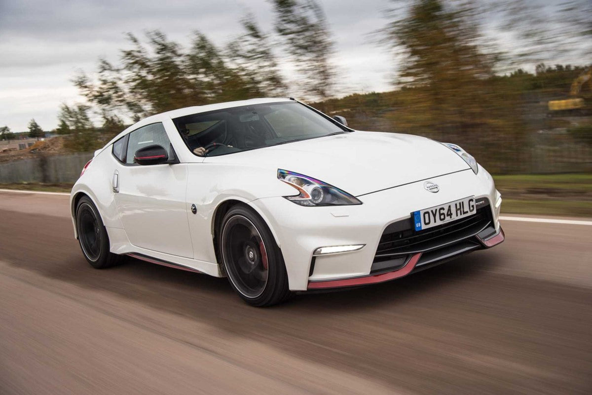 White Nissan 370Z Nismo sports car driving on a road with blurred background