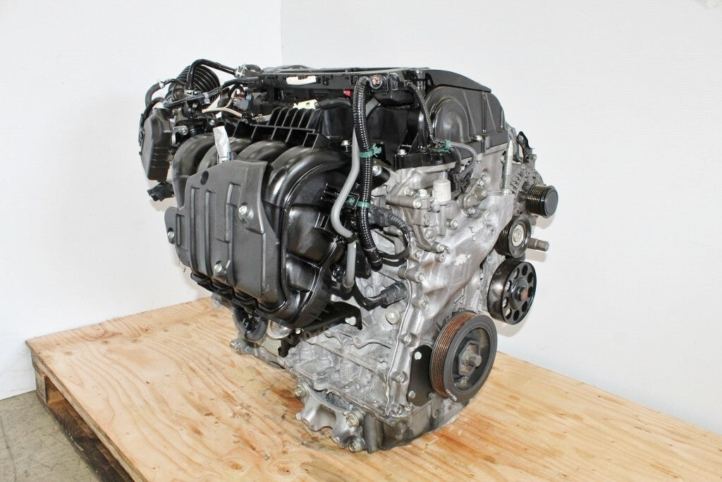 Used V6 car engine on wooden pallet against white background, automotive parts