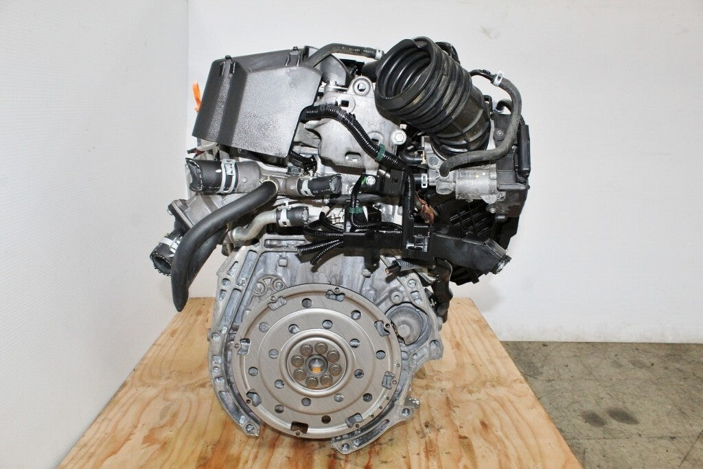 Used car engine with attached components on a wooden pallet in a workshop setting